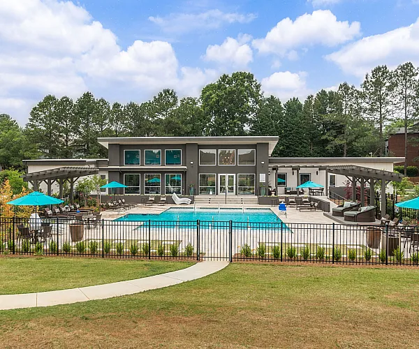 Luxurious apartment complex showcasing a stunning pool area, stylish modern clubhouse, and vibrant outdoor seating with umbrellas.