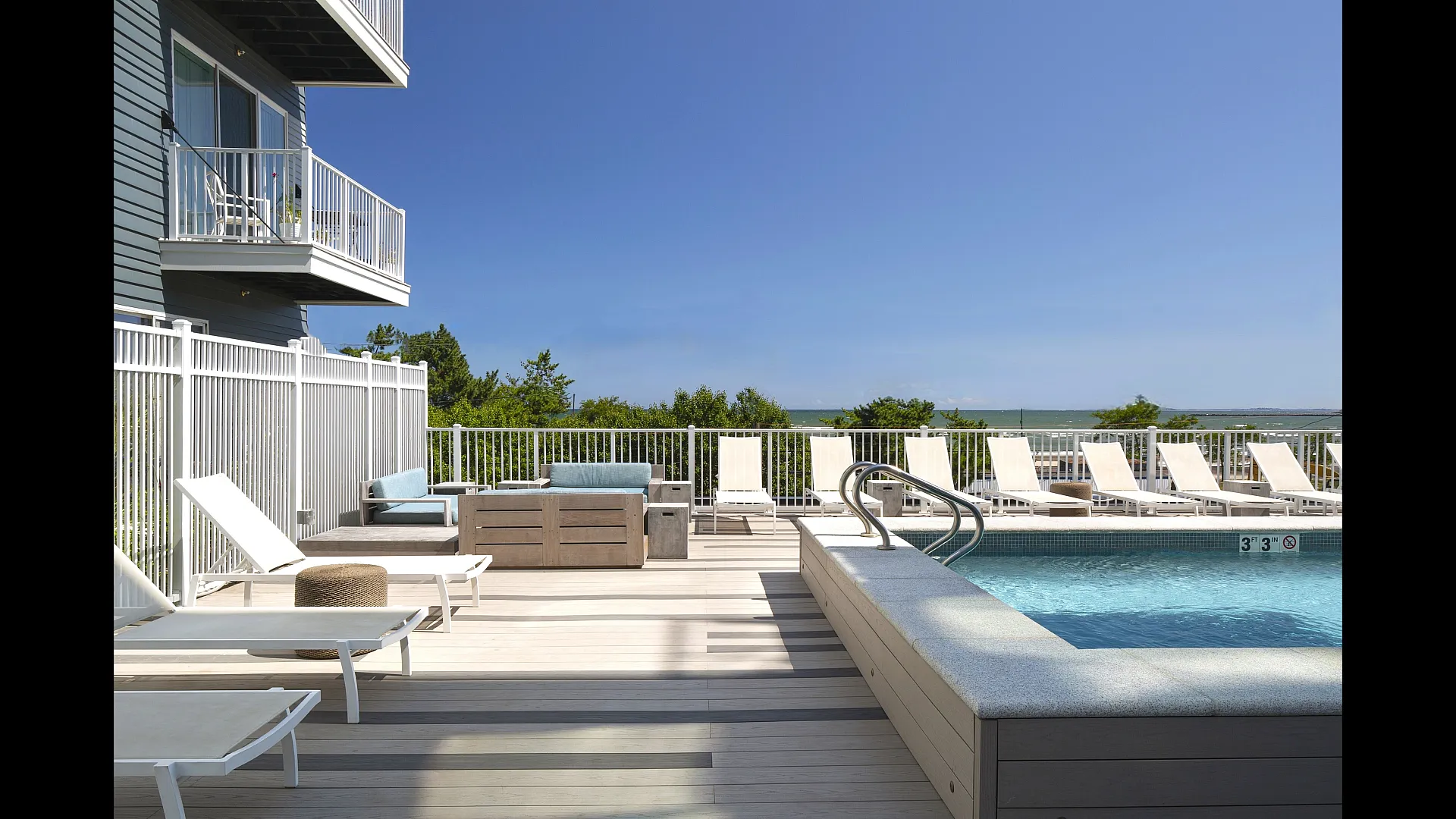 Luxurious poolside retreat featuring modern lounge chairs, vibrant blue sky, and scenic ocean views.
