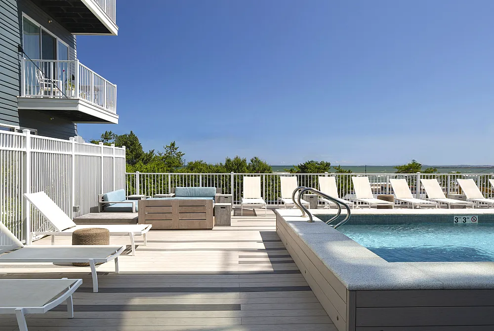 Inviting rooftop pool area with comfortable loungers, offering a serene ocean view and modern outdoor seating.