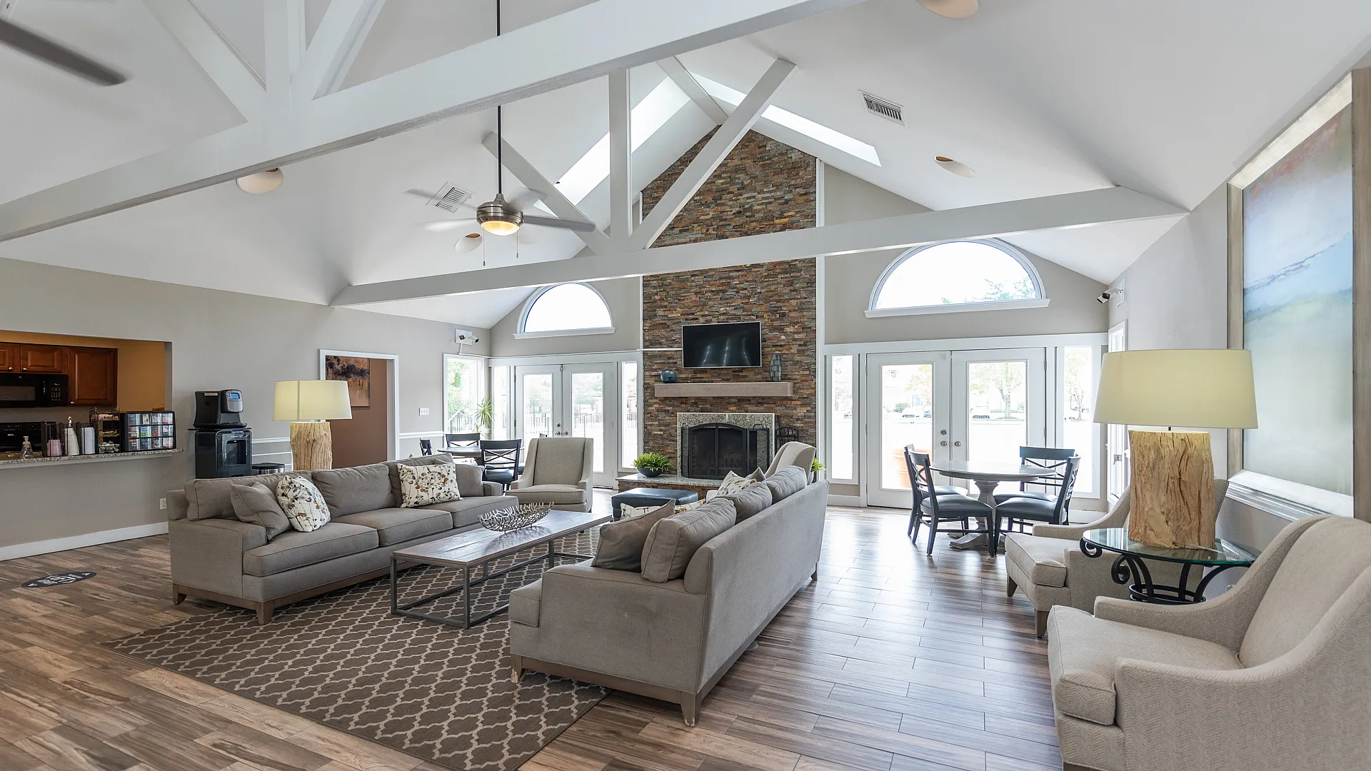 Elegant and spacious living room with vaulted ceilings, cozy sofas, large windows, and a stone fireplace.