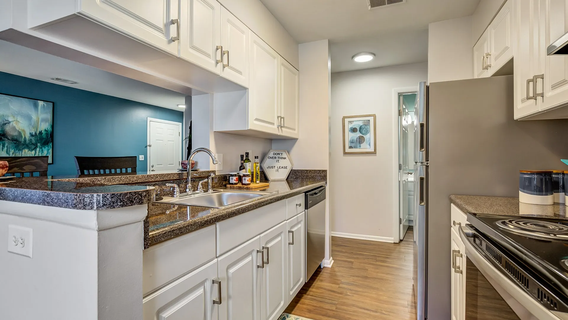 Modern kitchen featuring sleek countertops, stainless steel appliances, and elegant white cabinetry with a view into the inviting living area.