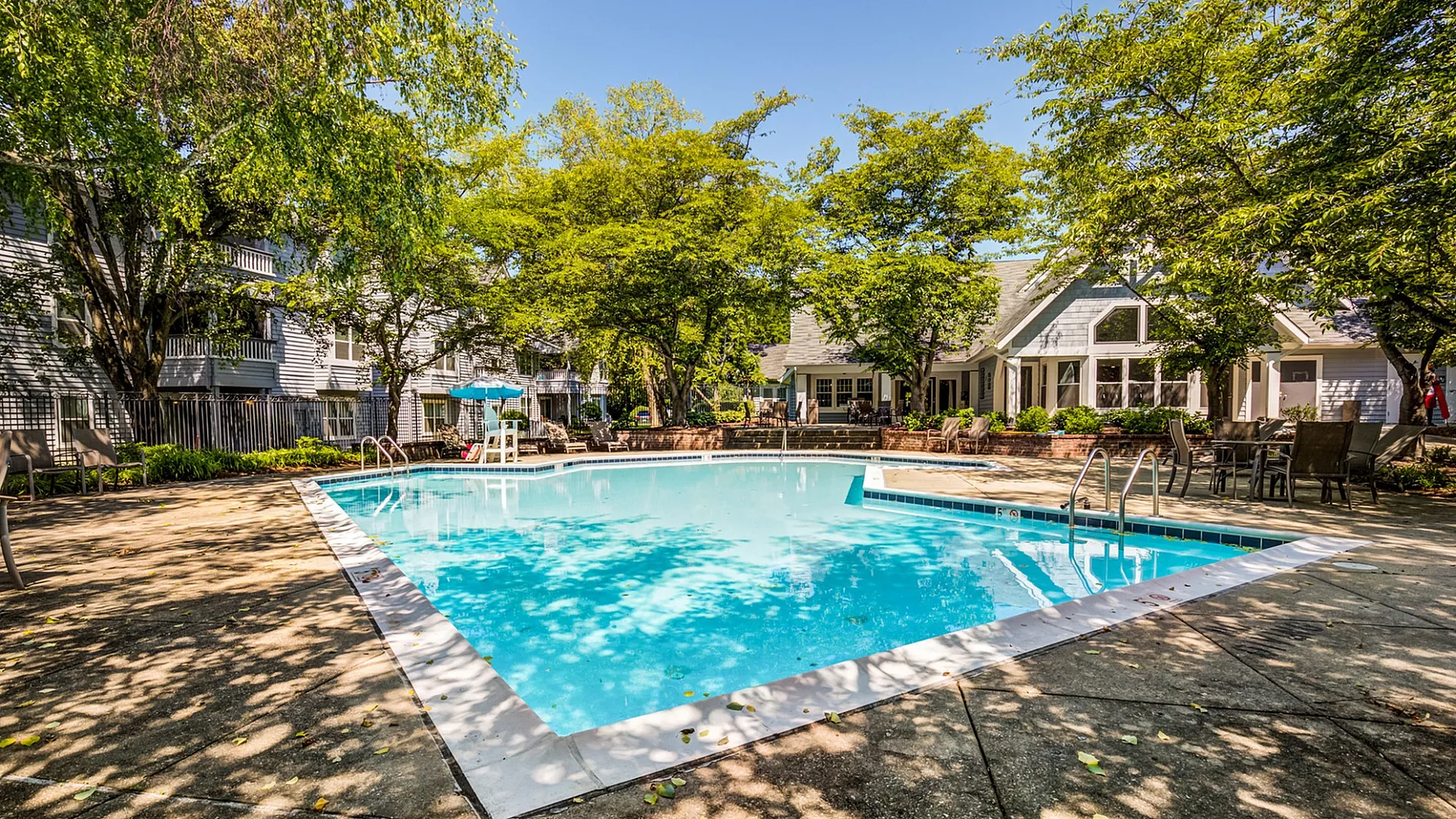 Inviting outdoor pool area surrounded by lush greenery and modern residences, perfect for relaxation.