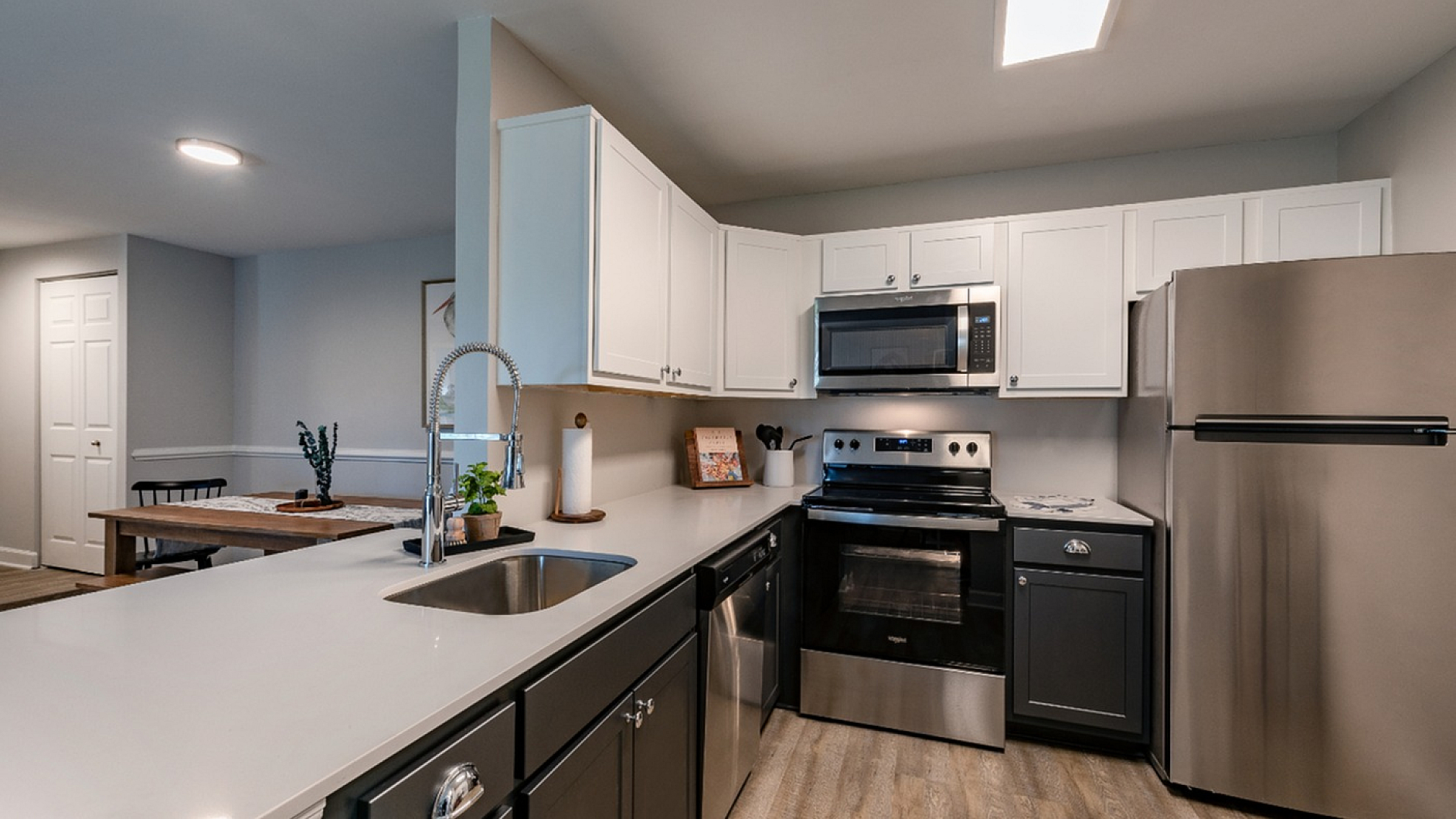 Modern kitchen with sleek stainless steel appliances, elegant white cabinets, and a chic dining nook for a stylish living experience.