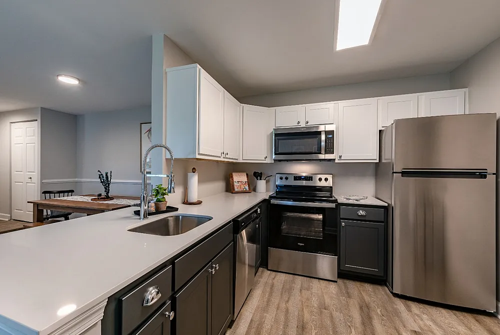Modern kitchen with sleek stainless steel appliances, elegant two-tone cabinets, and a spacious island countertop.