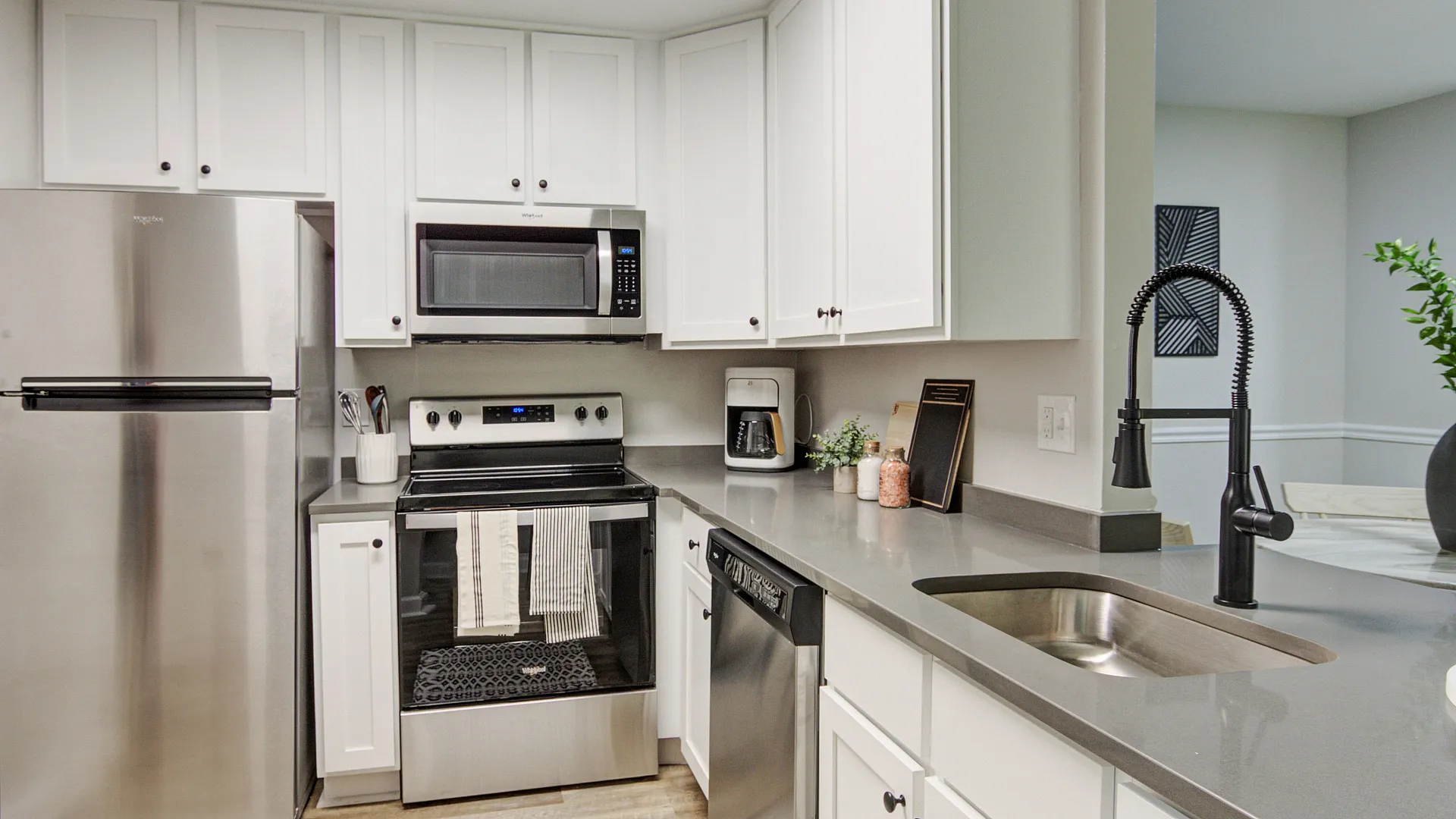 Modern kitchen boasting sleek stainless steel appliances, elegant white cabinetry, and a stylish faucet, creating a bright and inviting cooking space.