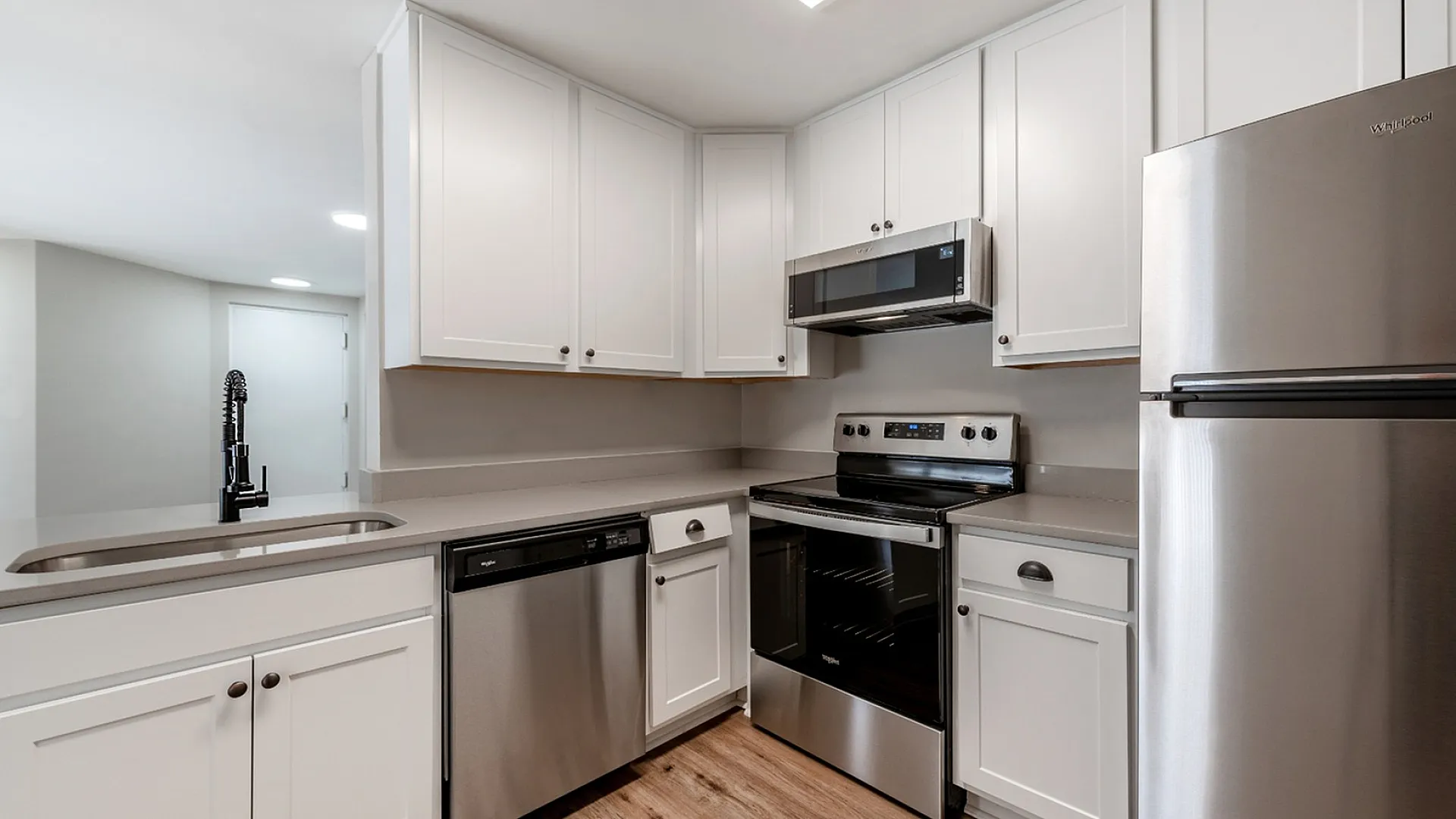 Modern kitchen with sleek stainless steel appliances, elegant white cabinetry, and a stylish faucet, enhancing a spacious and bright living area.