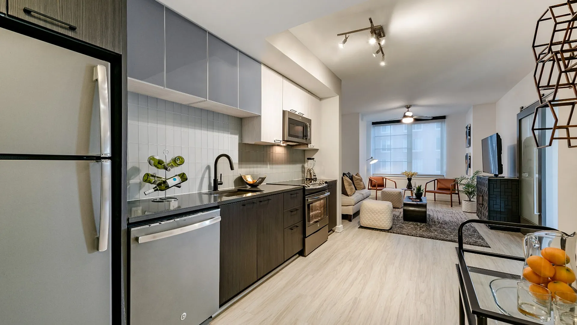 Modern open-concept apartment featuring a stylish kitchen with sleek appliances and a cozy living area drenched in natural light, perfect for entertaining.