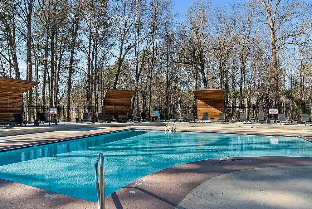 Inviting outdoor pool area surrounded by elegant lounge chairs and modern wooden canopies, perfect for relaxing afternoons.