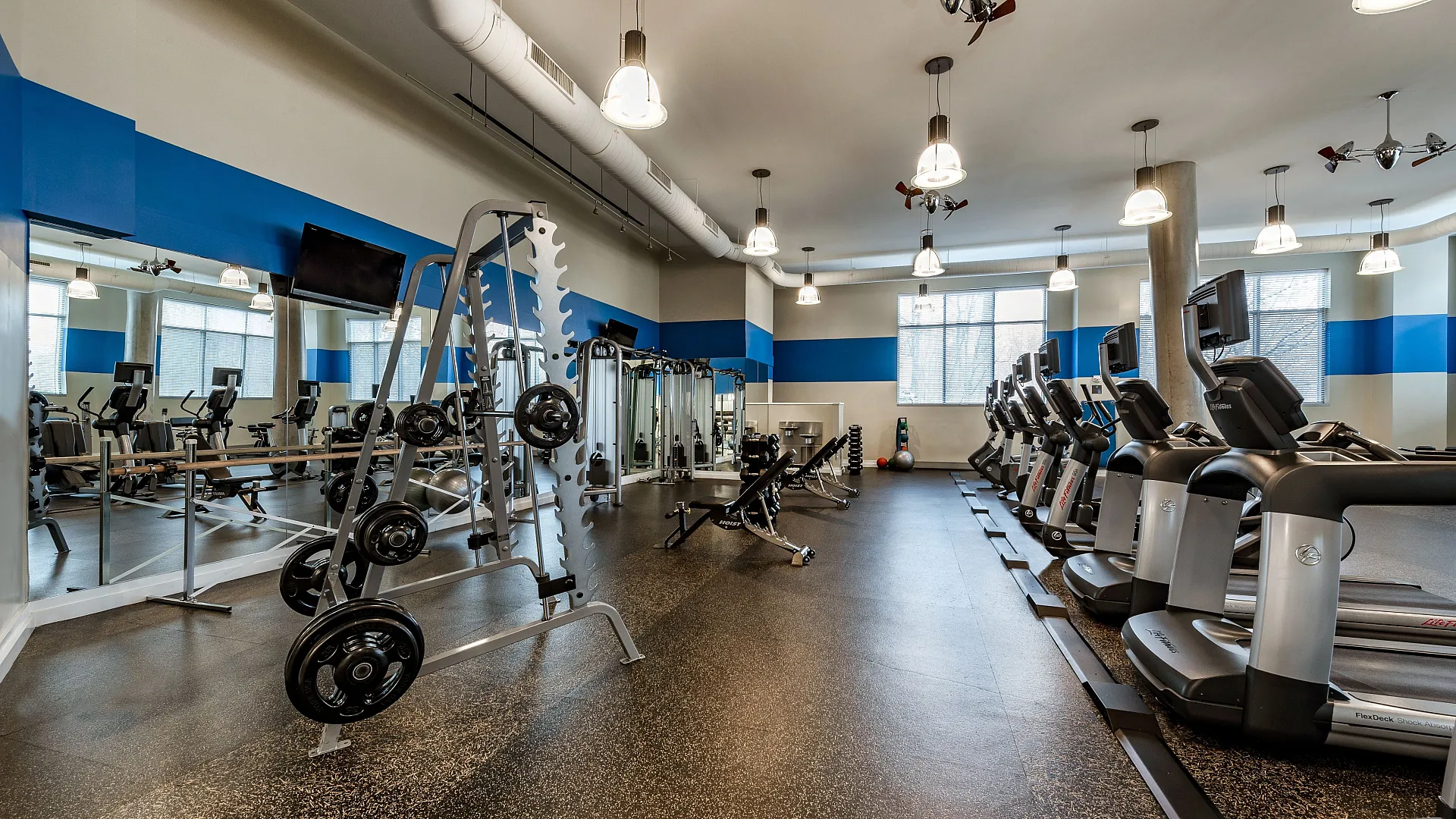 Modern fitness center featuring a range of state-of-the-art exercise equipment, bright lighting, and spacious workout areas.