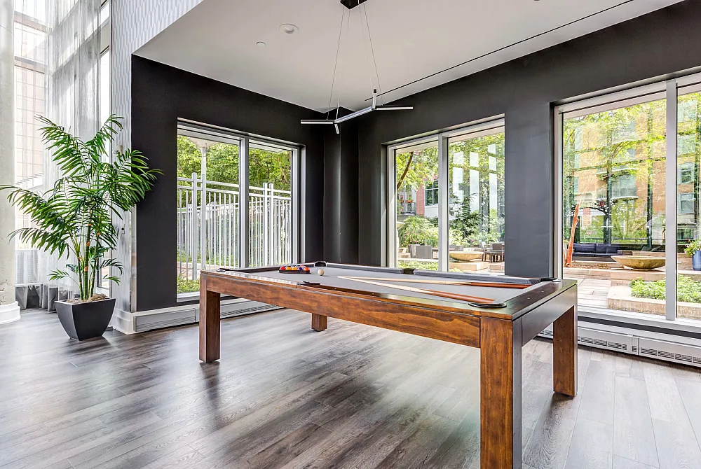 Elegant recreational room with modern billiards table and lush outdoor views through large windows, perfect for leisure and entertainment.