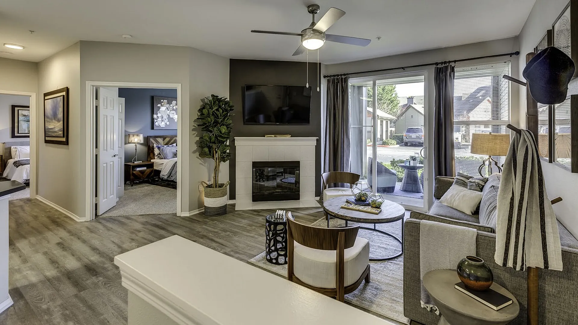 Bright and inviting living room with modern decor, featuring a cozy fireplace, stylish furniture, and sliding glass doors opening to a scenic outdoor view.
