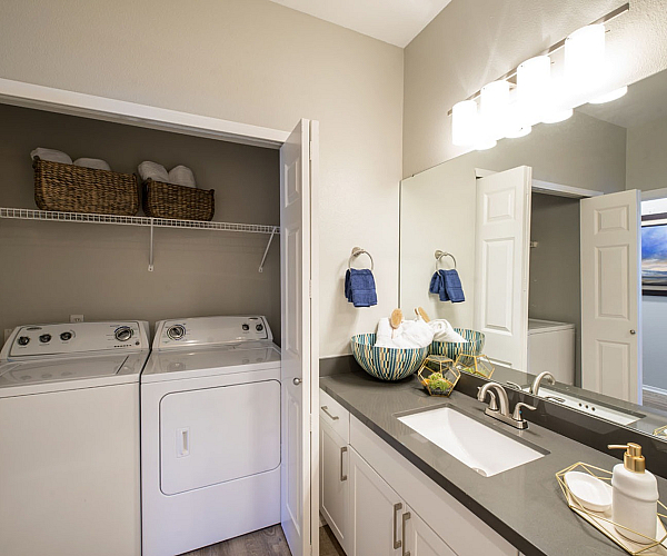 Chic apartment bathroom featuring modern fixtures, dual sink, and a convenient laundry area with washer and dryer.