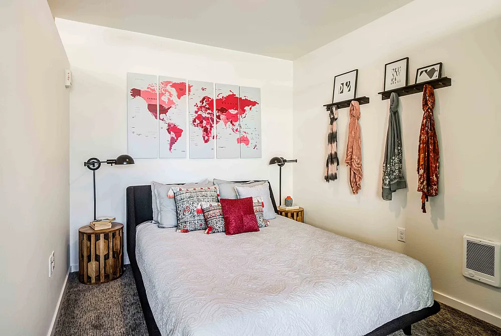 Cozy bedroom with a world map art piece above the bed, stylish throw pillows, and an elegant side table lamp.