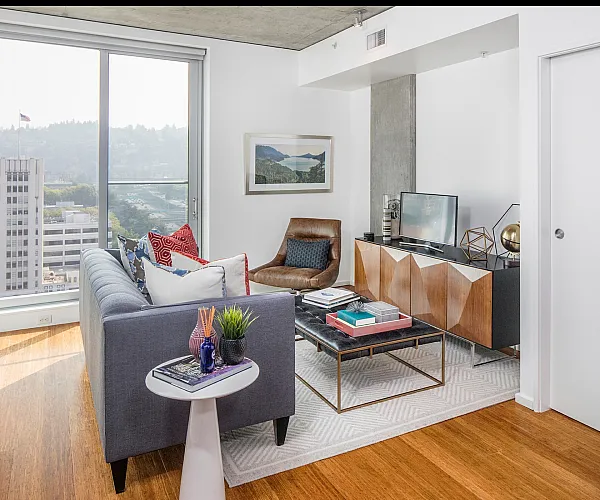 Modern living room with a cozy seating area, chic decor, and a stunning city view through large windows.