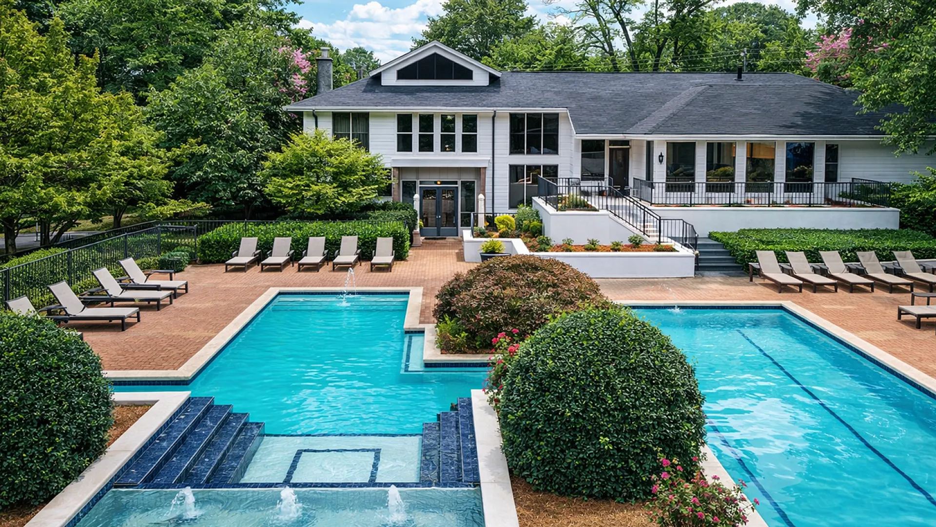 Luxurious apartment complex with an inviting outdoor pool, surrounded by lush greenery and stylish lounge chairs, offering a serene and upscale living environment.