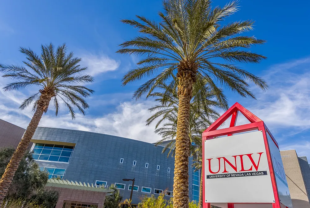 Vibrant campus scene with modern architecture, palm trees, and a bright blue sky at UNLV.