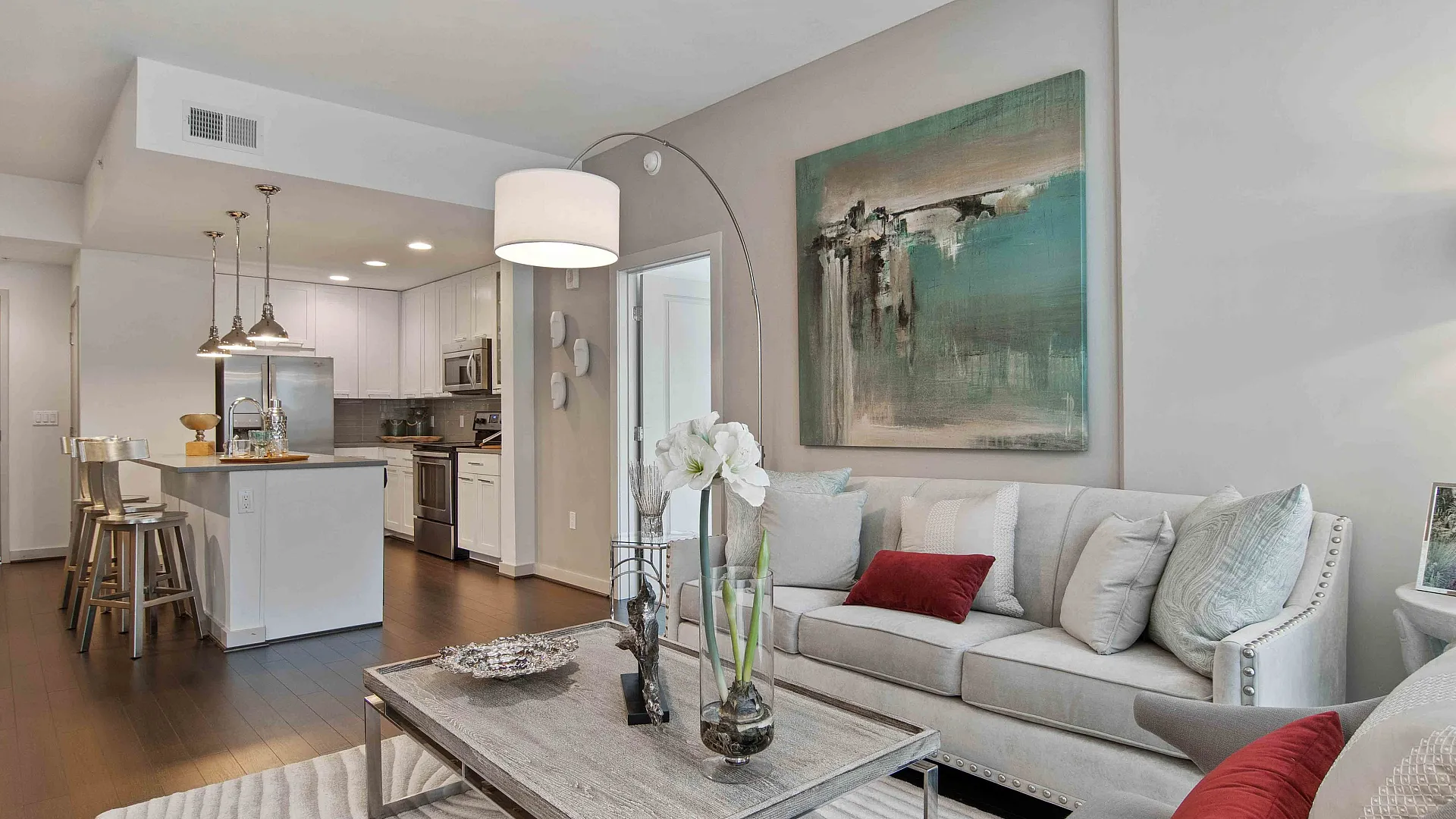 Inviting open-concept living space featuring a cozy sofa, elegant decor, and a modern kitchen with sleek appliances.