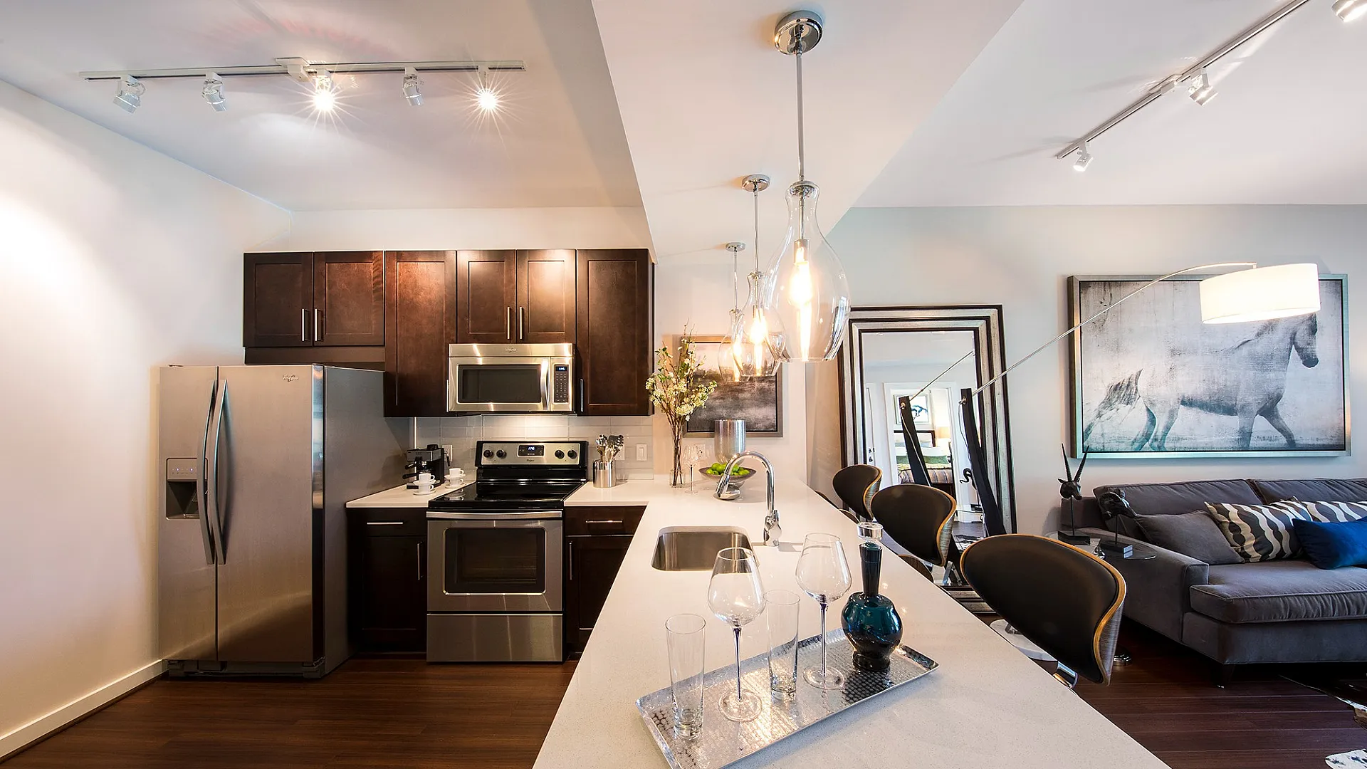 Chic apartment interior featuring a modern kitchen with stainless steel appliances, elegant pendant lighting, and a stylish living area with contemporary decor.
