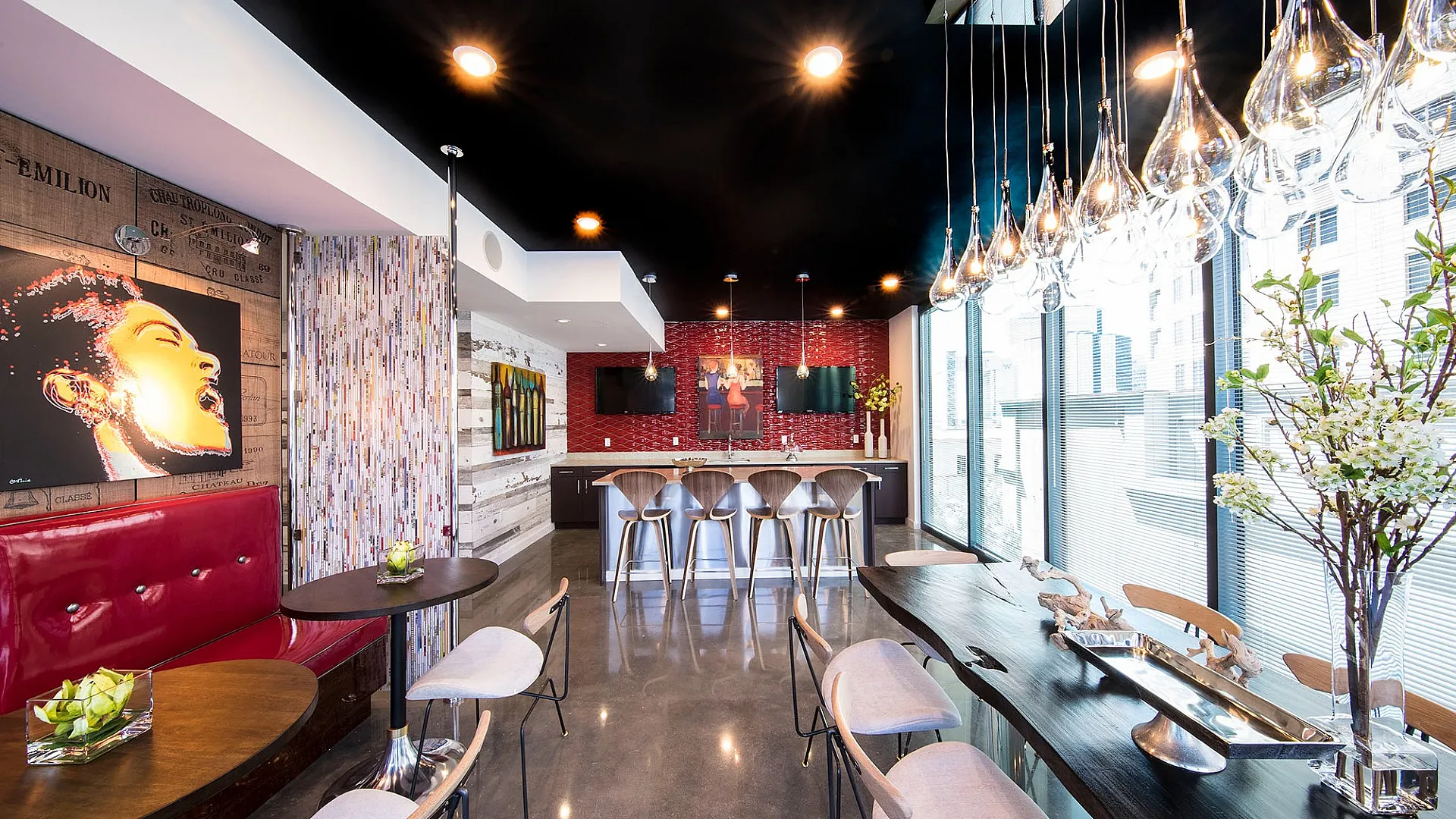 Chic urban lounge featuring modern art, sleek countertops, and vibrant red accents with large windows for natural light.