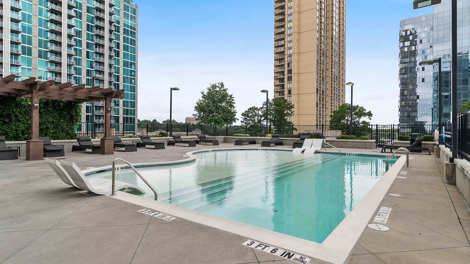 Elegant urban outdoor pool area with modern lounge chairs and sleek high-rise buildings in the background.