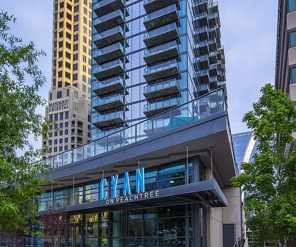 Modern skyscraper Cyan on Peachtree, featuring sleek glass architecture and elegant balconies, nestled in an urban environment.
