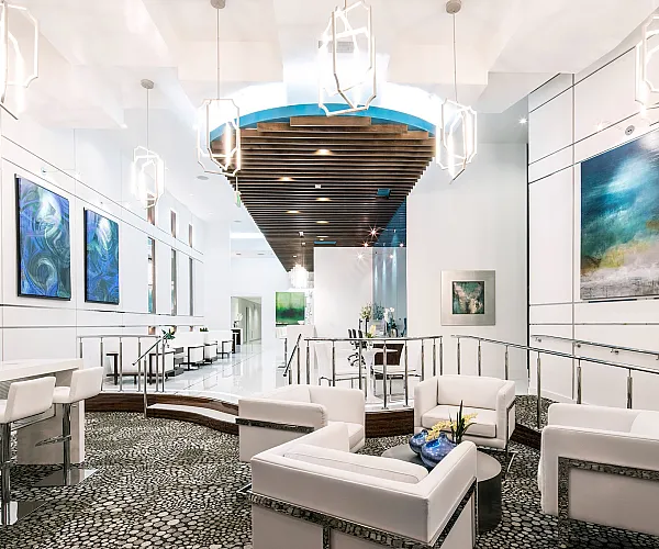 Luxurious modern lobby with elegant white seating, artistic paintings, and sophisticated lighting, offering a welcoming ambiance.