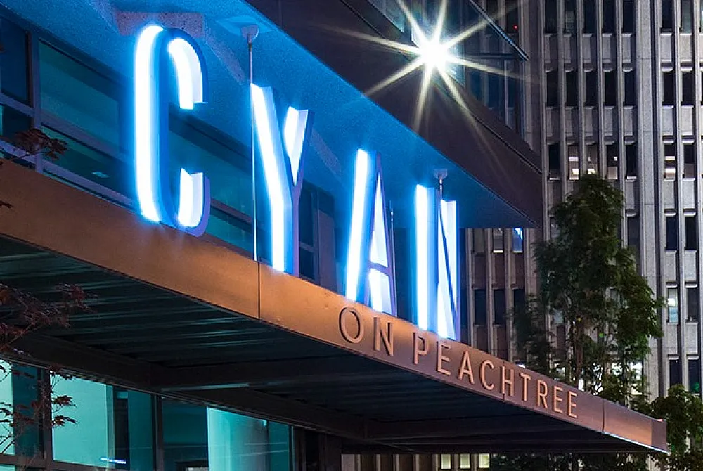 Vibrant urban night scene featuring stylish architecture of Cyan on Peachtree, with lively city lights and a welcoming sidewalk atmosphere.