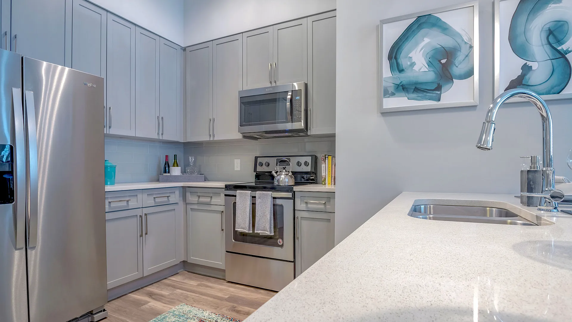 Contemporary kitchen with sleek stainless-steel appliances, elegant gray cabinetry, and vibrant artwork, exuding modern sophistication.
