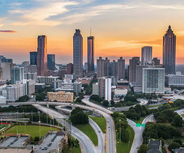 Breathtaking cityscape featuring dynamic skyscrapers and a vibrant sunset sky, offering urban living with scenic views.