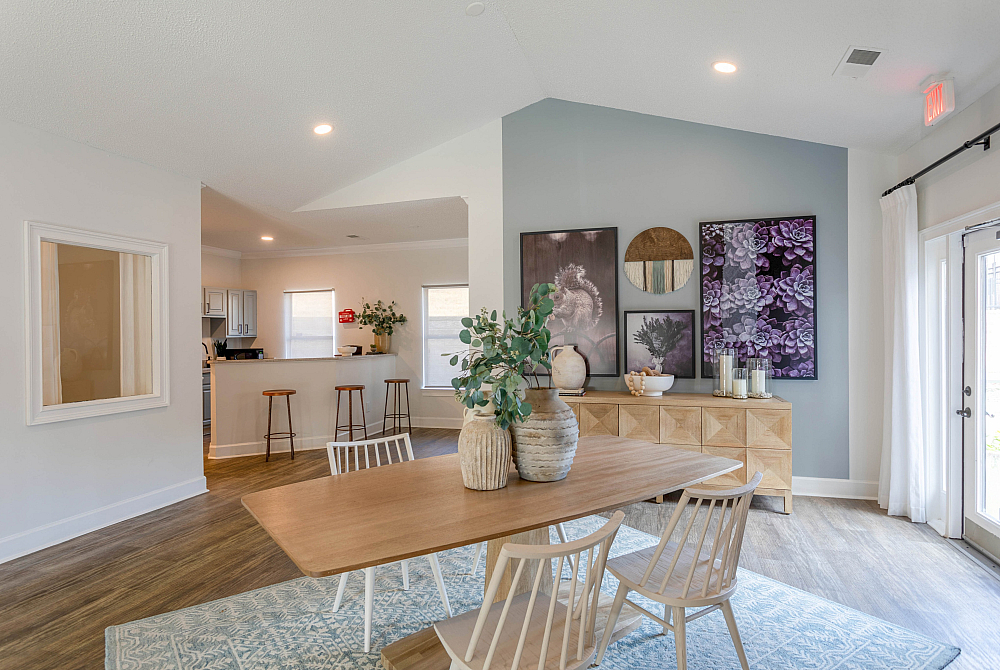 Chic open dining area with modern decor, featuring a wooden table, stylish chairs, and vibrant artwork, seamlessly blending into a cozy kitchen space with a breakfast bar.
