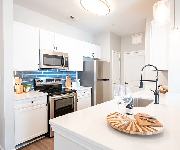 Bright and modern kitchen with sleek stainless steel appliances, elegant white cabinetry, and a stylish blue tile backsplash.