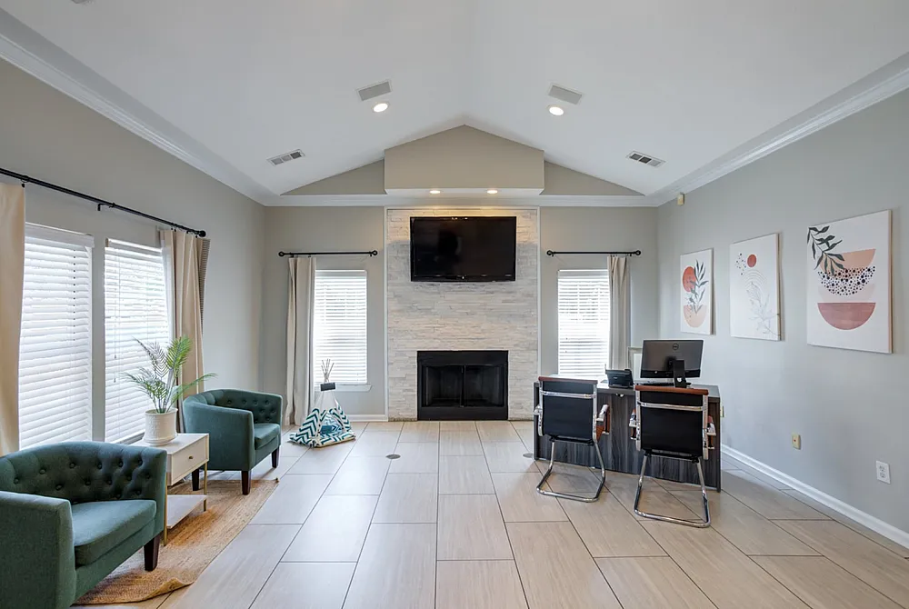 Elegant living room with modern decor, featuring a stone fireplace, large windows, stylish furniture, and contemporary art.