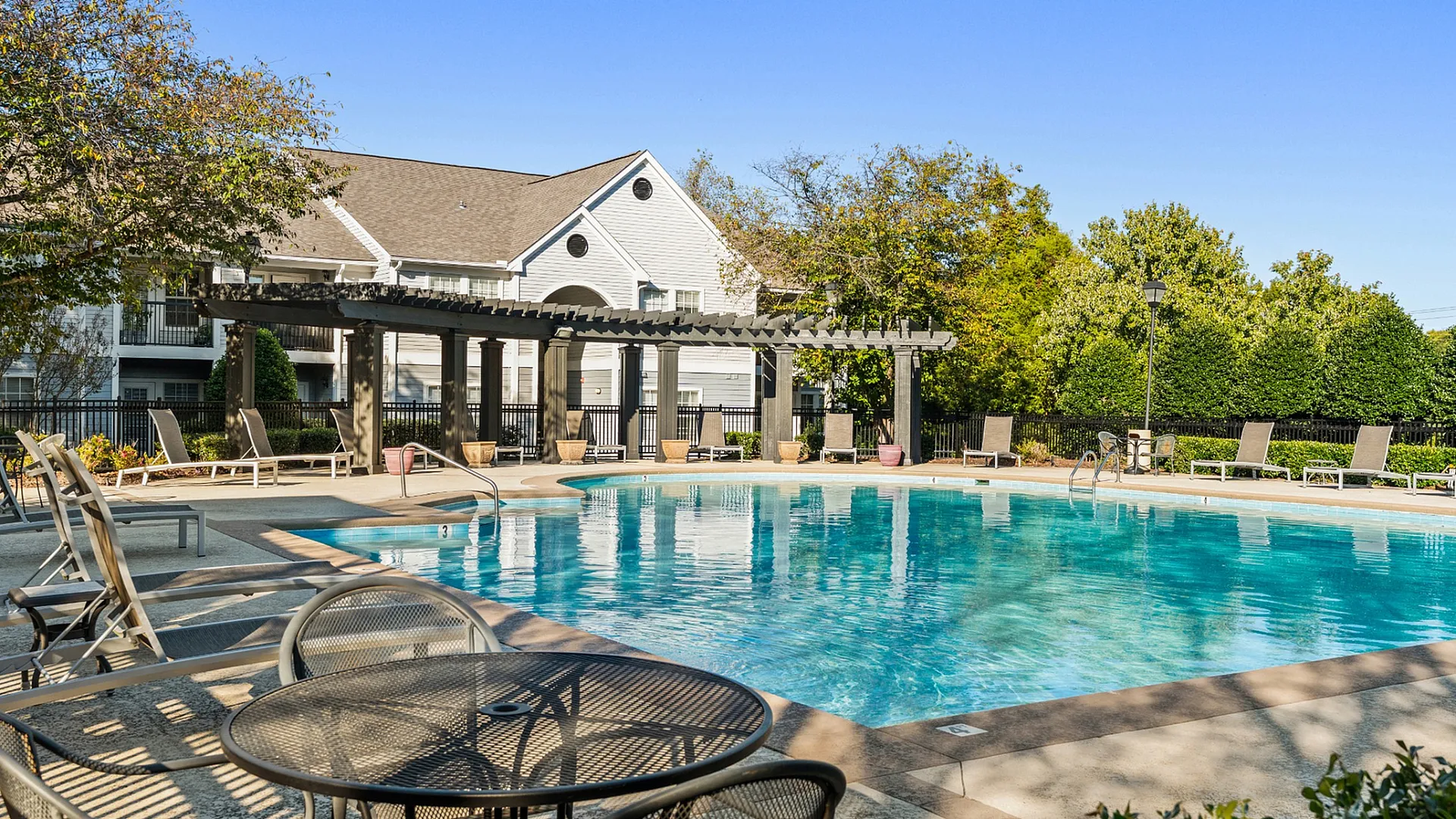 Elegant outdoor swimming pool with sun loungers and a shaded pergola, perfect for relaxation and leisure.