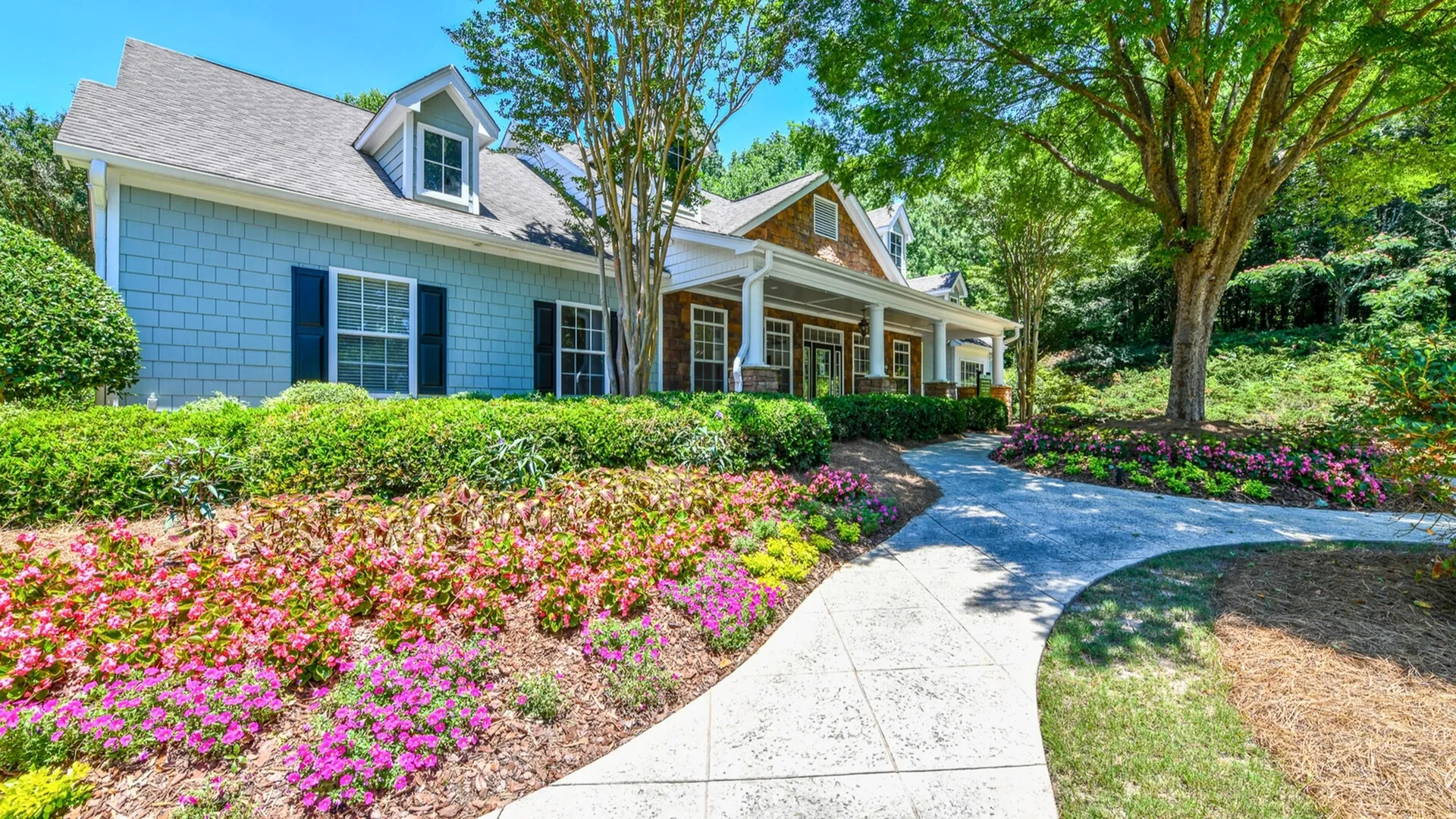 Charming suburban home with vibrant garden, lush greenery, and inviting walkway, perfect for tranquil living.