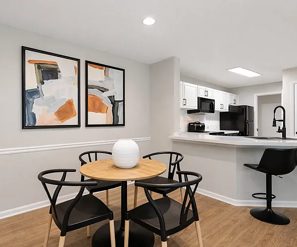 Chic, open-concept dining area with modern art and a contemporary kitchen featuring sleek black appliances.