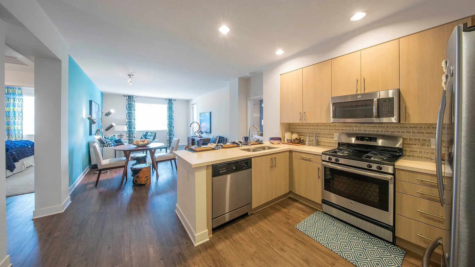 Modern open-concept apartment featuring a sleek kitchen with stainless steel appliances, a cozy dining area, and vibrant living space.