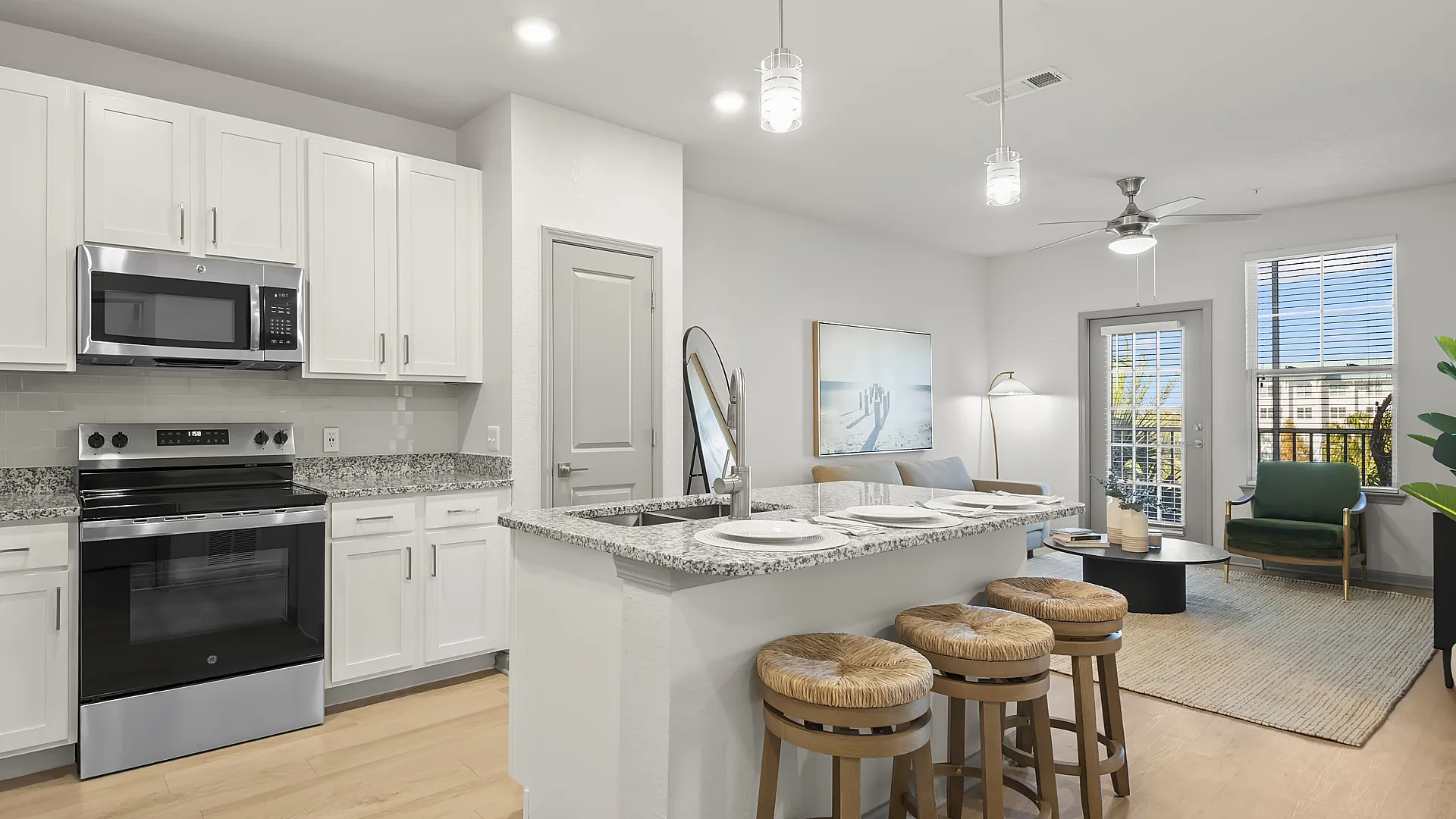 Modern open-concept kitchen and living area featuring sleek appliances, white cabinets, and stylish seating in a bright, inviting space.