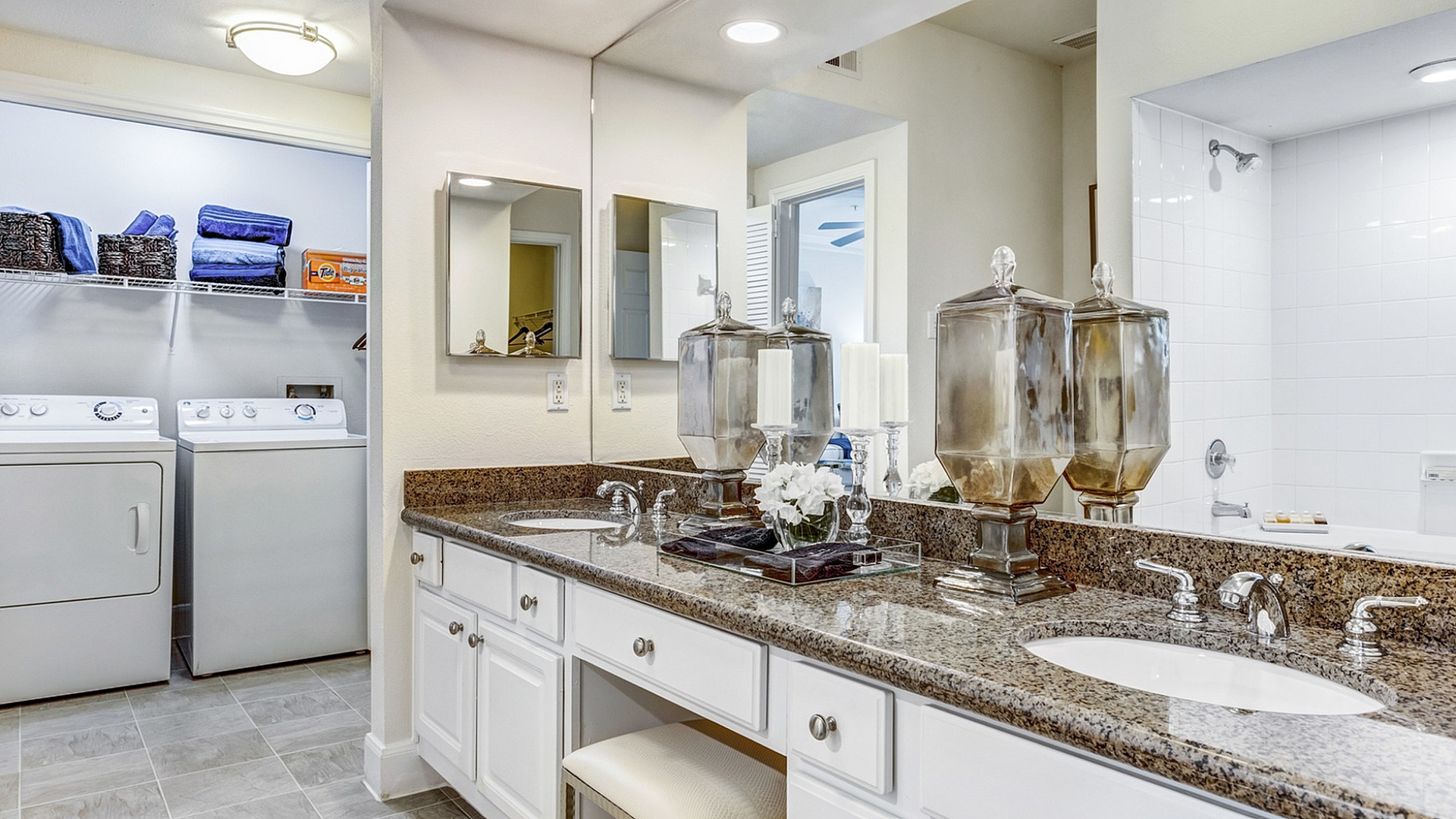 Elegant bathroom with double granite sinks, stylish decor, and nearby laundry area for convenience.