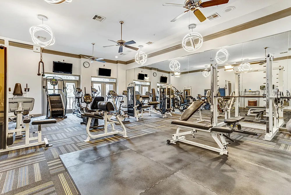 Elegant fitness center with state-of-the-art gym equipment, large mirrors, and modern lighting for an invigorating workout experience.