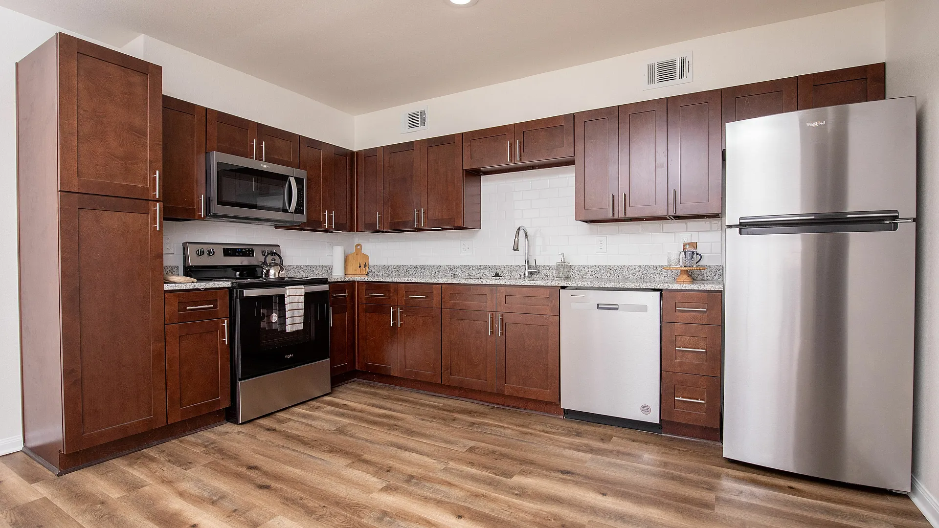 Modern kitchen with elegant dark wood cabinets, stainless steel appliances, and sleek hardwood flooring.