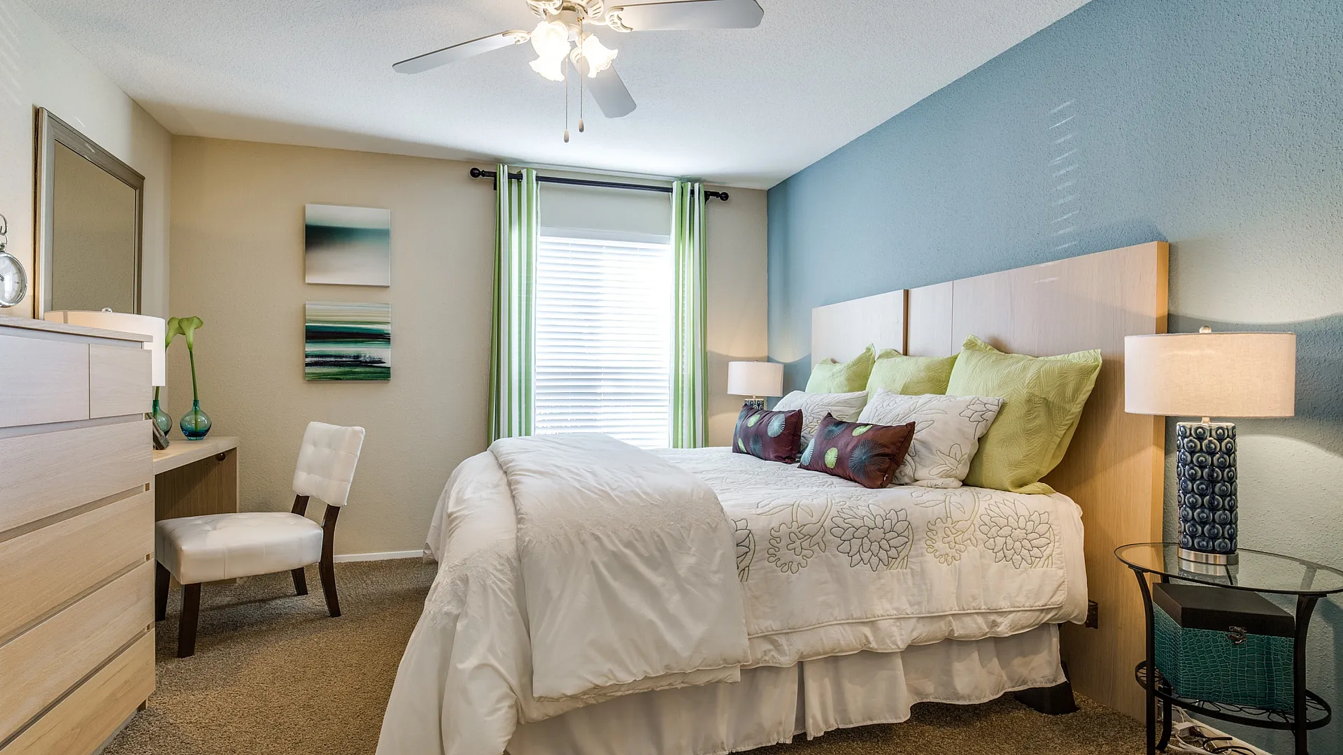 Inviting bedroom with chic decor, featuring elegant wall art, cozy bedding, and modern wooden furniture bathed in natural light.
