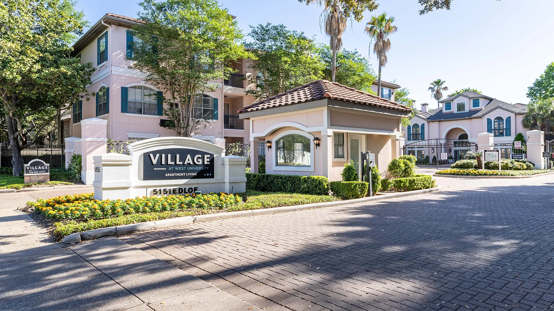 Charming apartment complex entrance at Village at West University, showcasing beautifully landscaped surroundings and elegant architecture.
