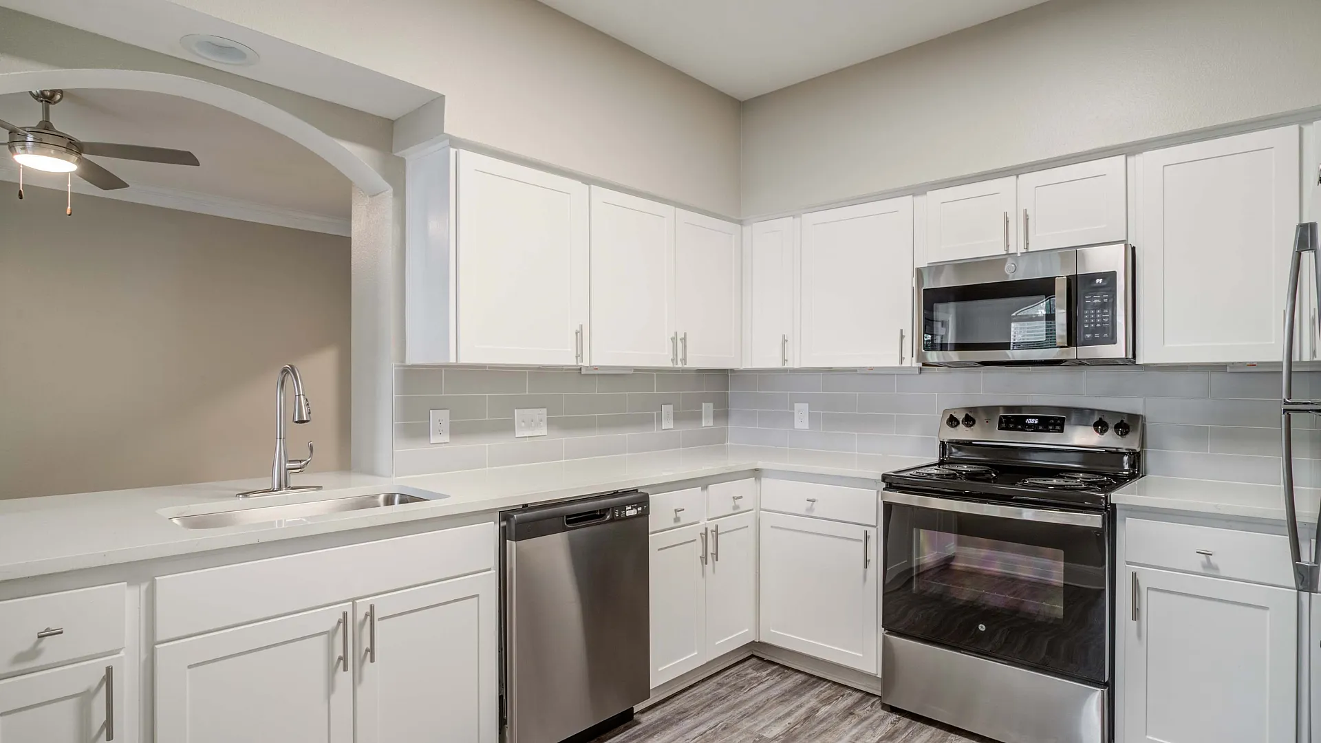 Elegant modern kitchen with sleek stainless steel appliances, white cabinetry, and stylish gray backsplash.