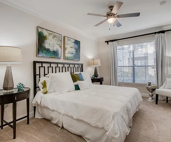 Elegant bedroom with modern decor, plush bedding, and serene artwork, offering a cozy retreat with ample natural light.