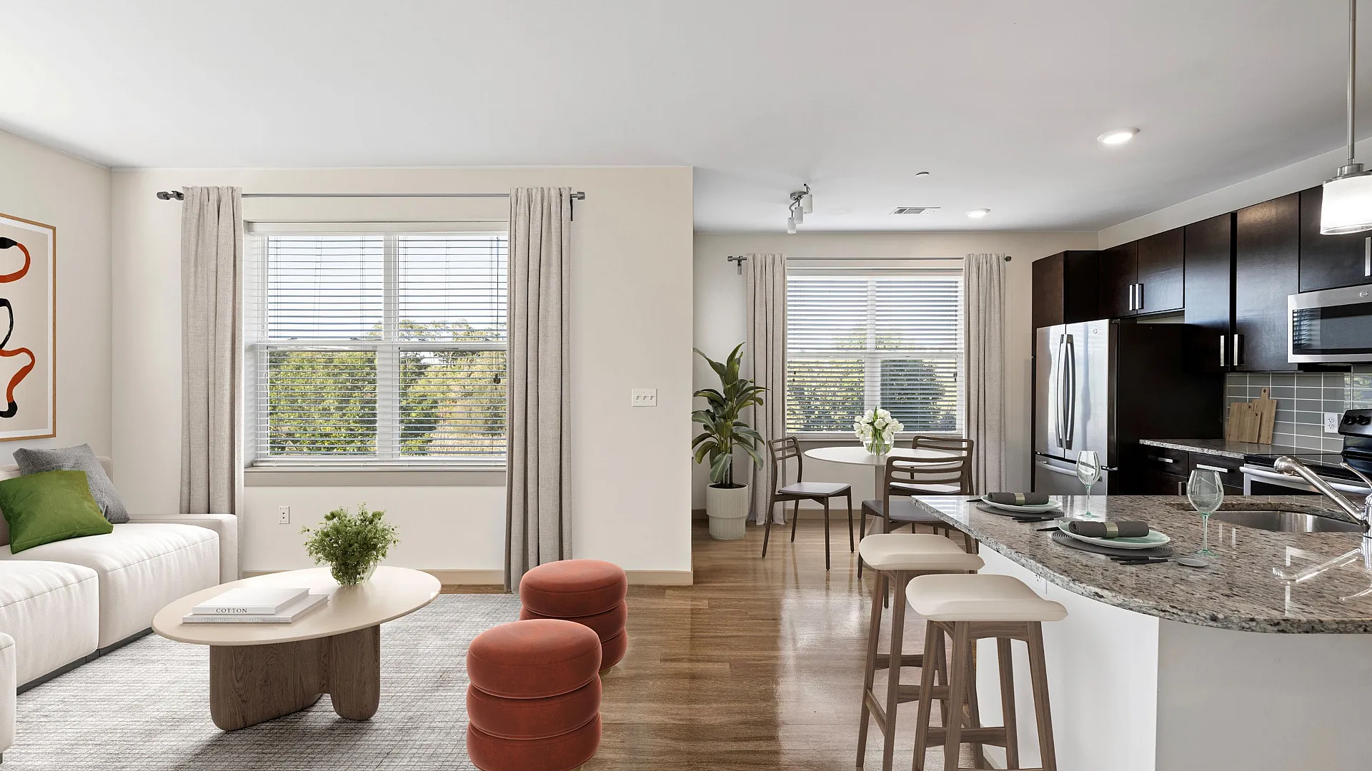 Bright open-plan living room with modern kitchen, elegant seating area, and large windows offering natural light.