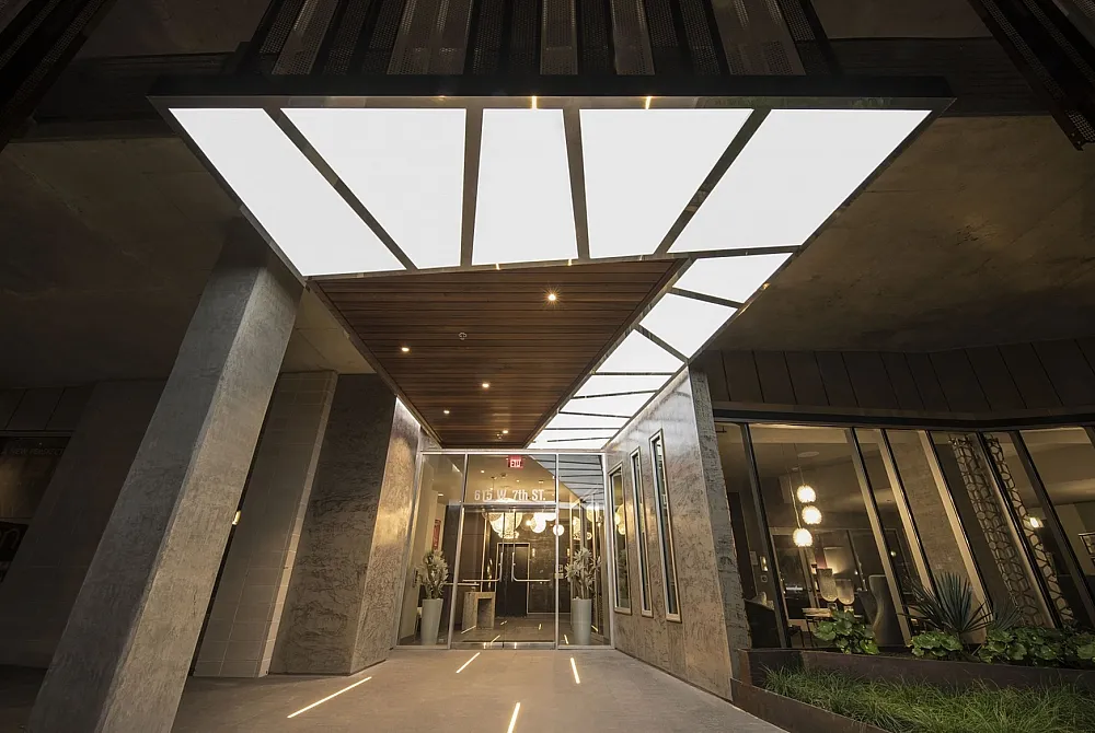 Modern apartment entrance featuring sleek architectural design, luminous skylights, and inviting greenery.
