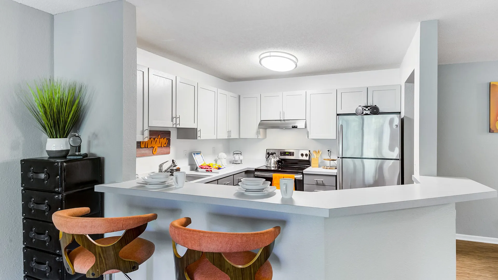 Modern kitchen with sleek white cabinets, stainless steel appliances, and a stylish breakfast bar with seating.