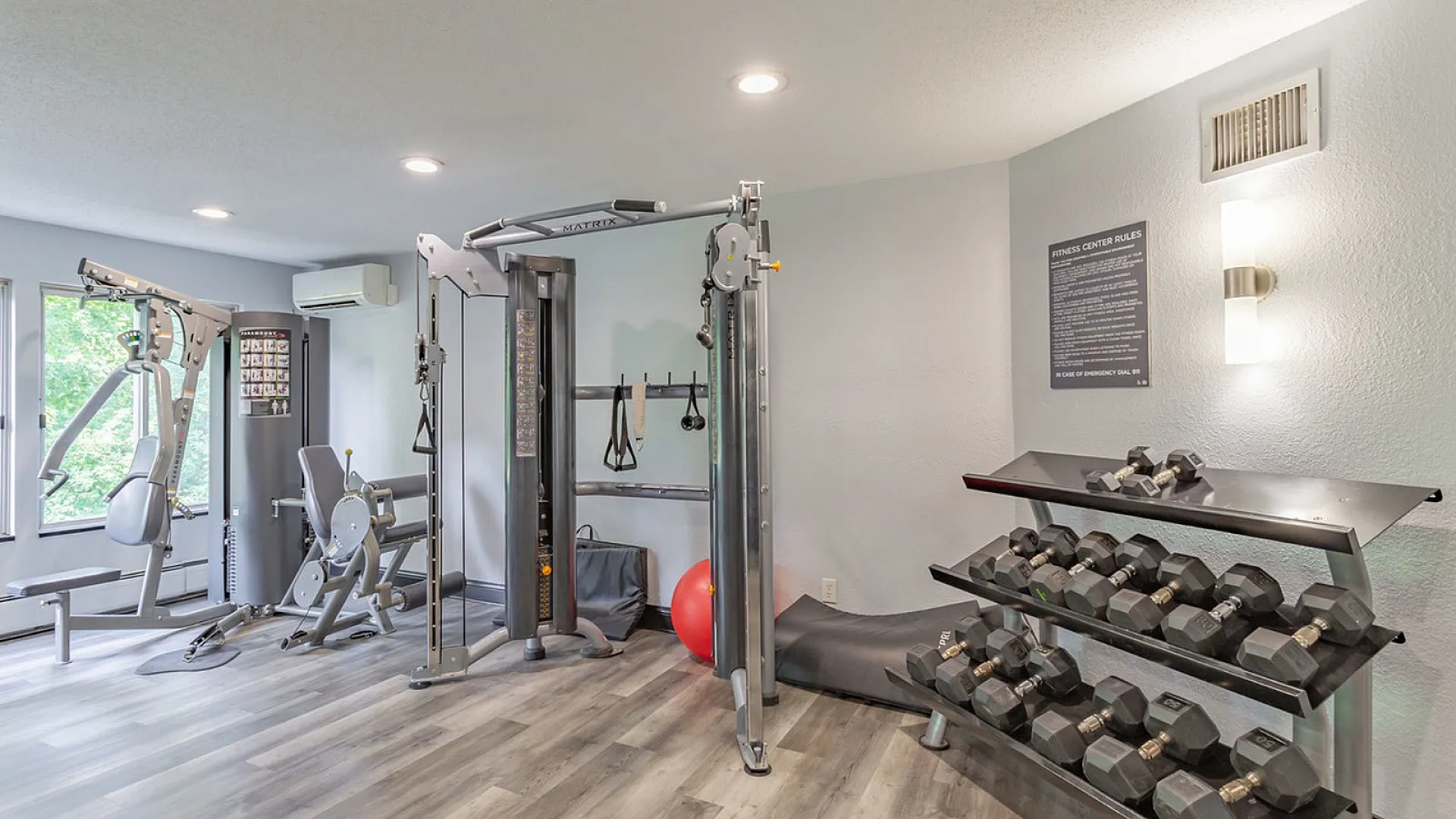 Modern apartment fitness center with state-of-the-art equipment, including a weight rack, resistance machines, and spacious layout.