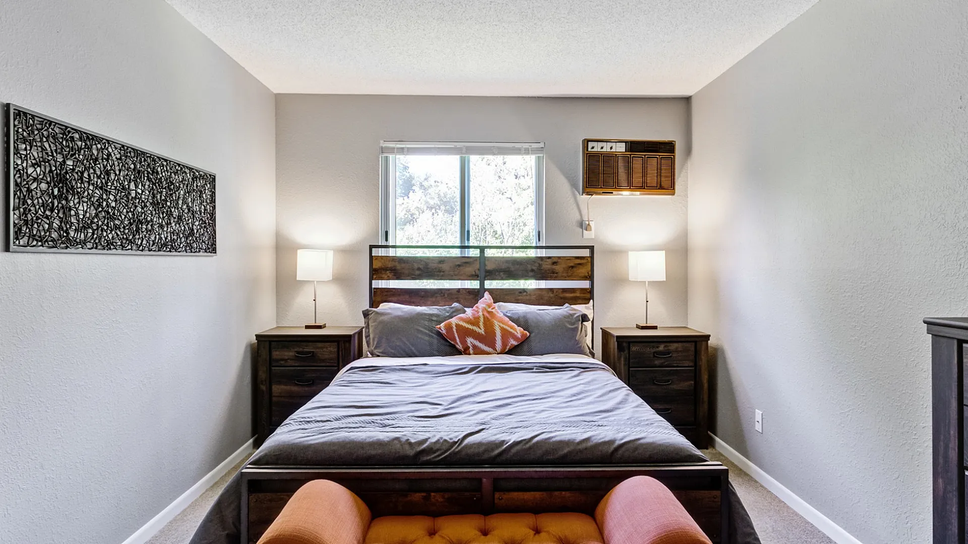 Inviting bedroom with a cozy queen-sized bed, modern decor, and warm lighting, showcasing comfort and style.