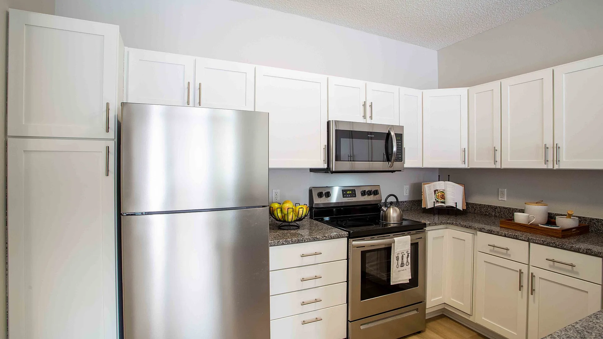 Contemporary kitchen with sleek stainless steel appliances, granite countertops, and elegant white cabinetry.